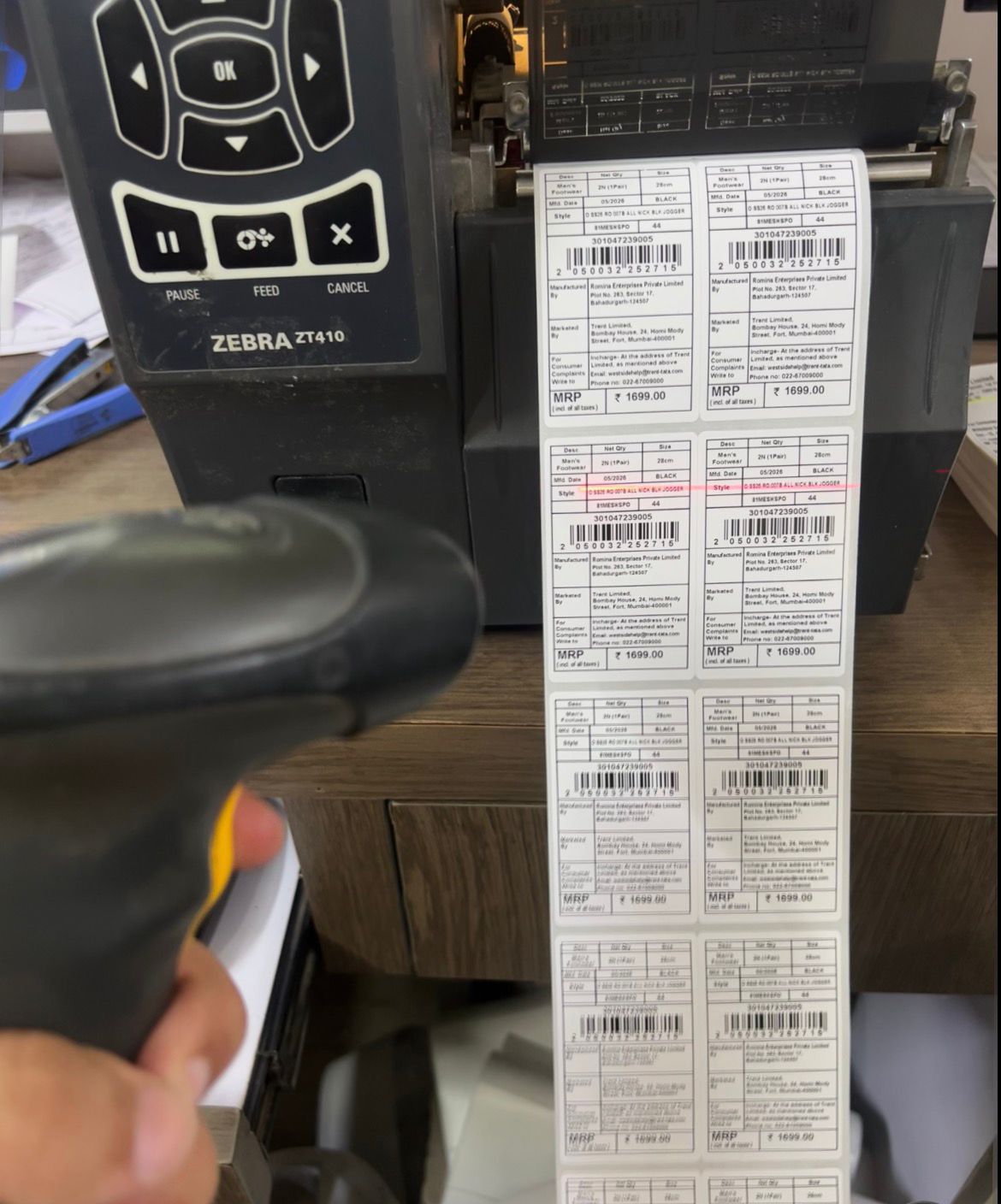 A hand scanner reading a printed barcode label to confirm it decodes